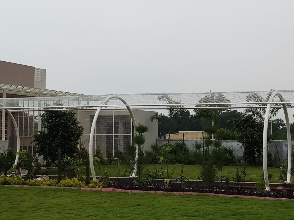 Curved canopy structure beside a landscaped building